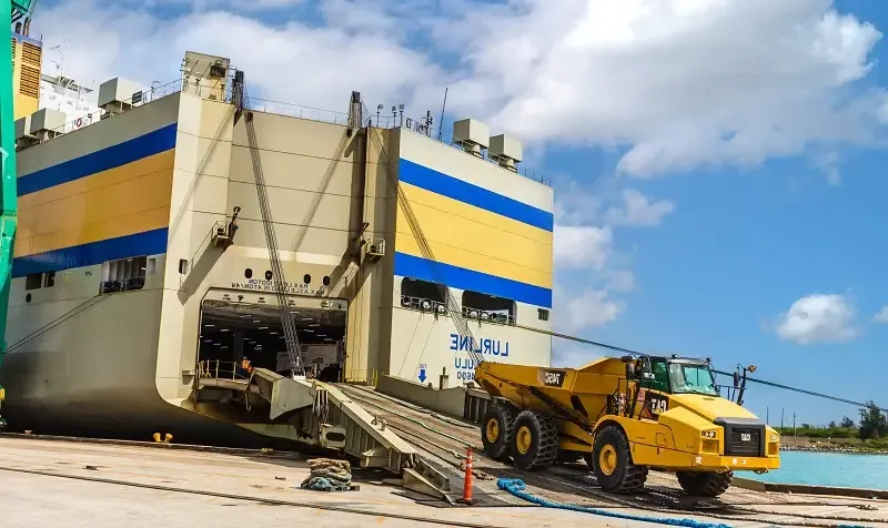 黄色的超大重型设备驶下滚装集装箱船Lurline的坡道.